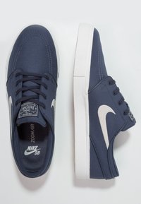 Sneaker Nike SB Zoom Air in blu navy con logo swoosh bianco, lacci neri e suole in gomma bianca, mostrati da angolazioni superiori e laterali.