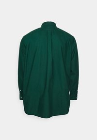 Långärmad skjorta i mörkgrön, i bomullstyg. Har en klassisk krage och knäppta ärmslut. Bakifrån visar den en jämn, enfärgad textur.