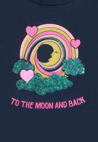 Ein navyblaues T-Shirt mit einem glitzernden, kreisförmigen Regenbogendesign mit einem Mond und einem Gesicht, grünen Paillettenwolken und pinken Herzen. Der Text lautet: "ZUM MOND UND ZURÜCK."