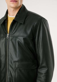 Chaqueta de cuero negra con collar clásico, cierre de cremallera y dos bolsillos frontales, con una textura suave y un diseño ajustado.