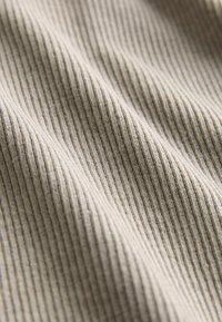 Jasno beżowy tekstyl o prążkowanej strukturze, z równomiernie rozstawionymi pionowymi liniami, miękka tkanina i gładkie, matowe wykończenie.