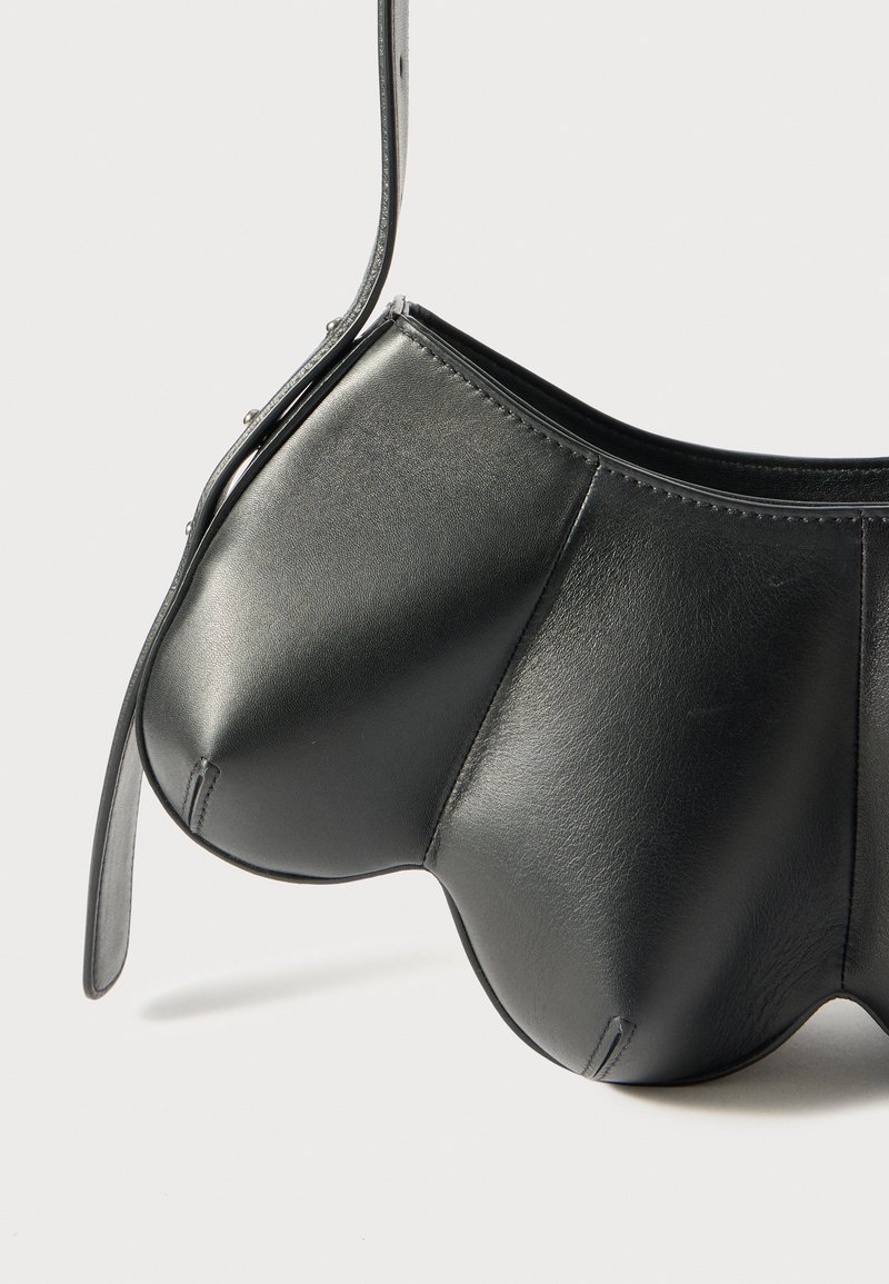 Zwarte leren handtas met een unieke gebogen vorm en een soepele textuur. Voorzien van een ritssluiting en een slanke schouderband om te dragen.