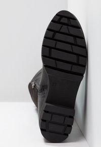 Bottine noire à surface texturée, dotée d'une fermeture éclair. La semelle présente des crampons antidérapants et des marquages, la taille 37 est imprimée sur le côté.