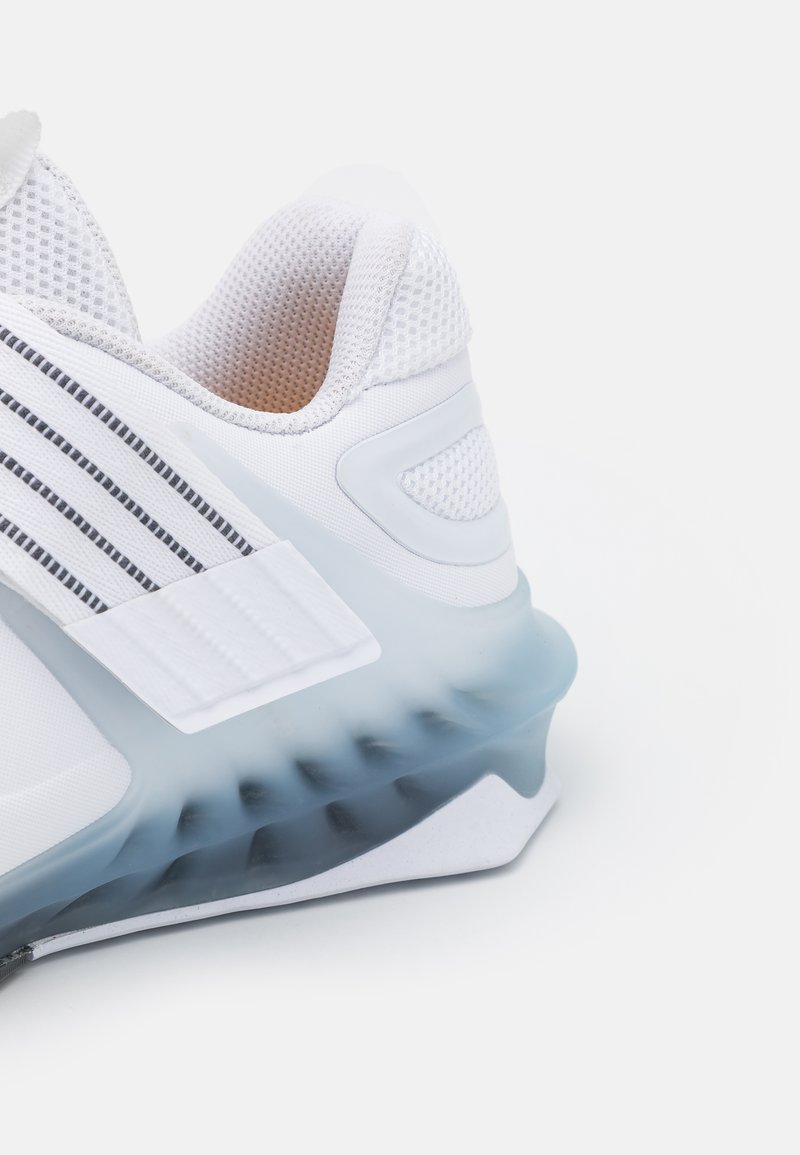 Weißer Sportschuh mit einem strukturierten Mesh-Obermaterial. Verfügt über eine klare blaue Laufsohle und schwarze Streifenakzente. Abgerundetes Design mit gepolstertem Kragen.