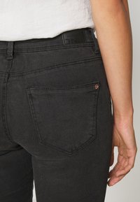 Zwarte denim jeans met een slim fit, voorzien van achterzakken, zichtbare stiksels en een leren logo-label op de tailleband.