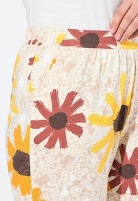 Katoenen bloemenbroek met een beige achtergrond, voorzien van grote rode en gele bloemenpatronen, elastische tailleband en gestructureerde stof.