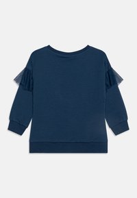 Top de manga larga azul marino con acentos de tul con volantes en los hombros, tejido suave, cuello redondo y puños y dobladillo elásticos.