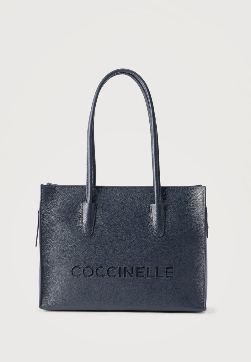 Τσάντα χειρός από δέρμα σε ναυτικό μπλε χρώμα με μακριά χερούλια, ορθογώνιο σχήμα και ανάγλυφο λογότυπο "COCCINELLE" στο κέντρο της πρόσοψης.