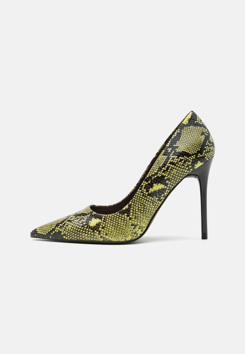 Chaussure à talon haut à bout pointu avec motif peau de serpent jaune et noir, talon stiletto fin sur fond blanc.