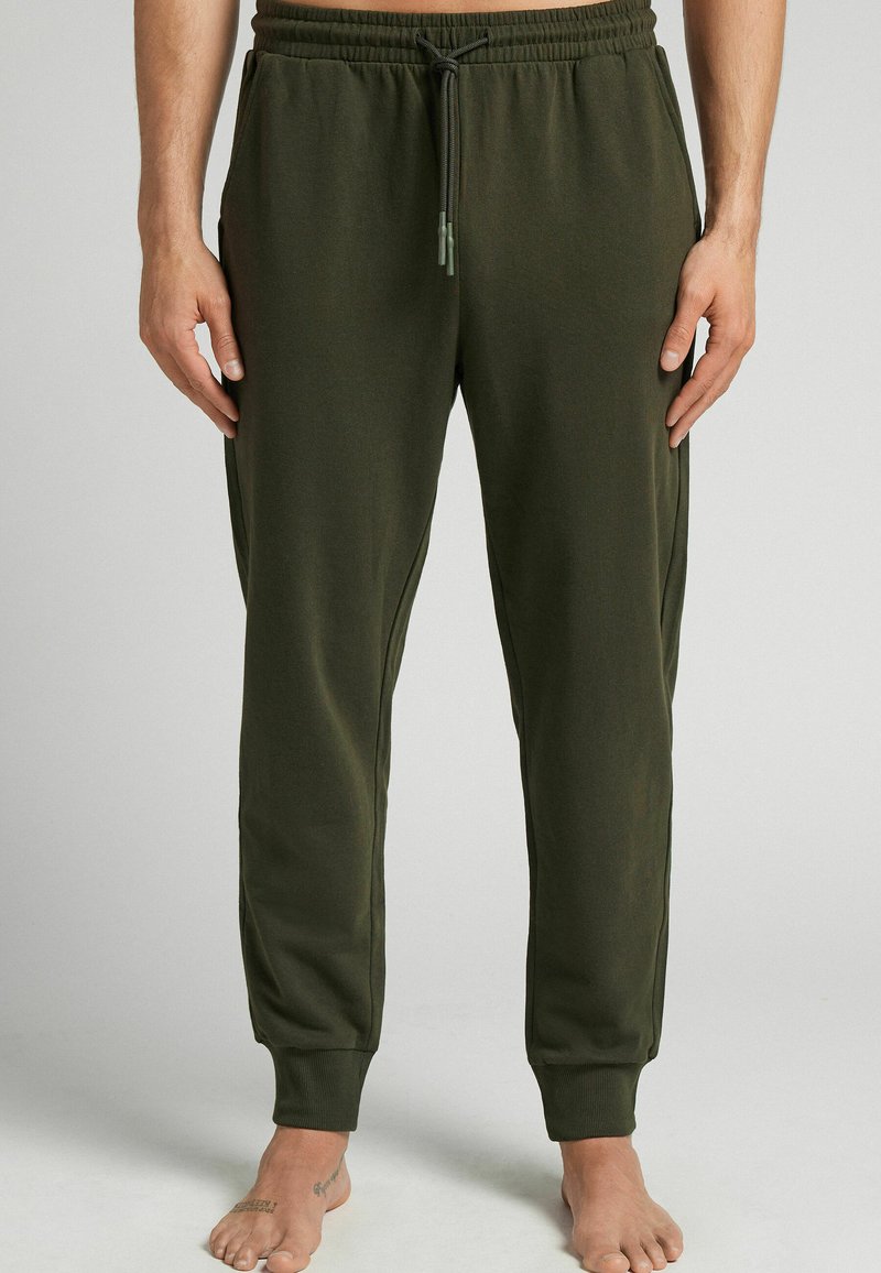 Groene joggingsbroek voor heren van zacht fabric, met een elastische tailleband en een koord, en geribbelde boorden.