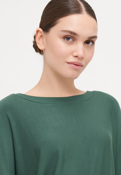 Sweater verde oversized com um decote amplo, feito de tecido suave, com textura canelada e mangas longas. Design limpo e simples.