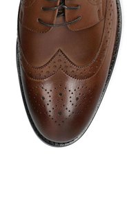 Brązowe skórzane buty do garnituru z misternym detalem brogu, spiczastym noskiem i czarnymi sznurówkami. Gładka tekstura z wypolerowanym wykończeniem i dekoracyjnymi perforacjami.