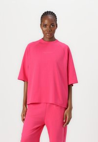Rosa bomullsoverstørrelse sweatshirt med rund hals og korte ermer, med merkevarenavnet "CARLO COLUCCI" på forsiden.