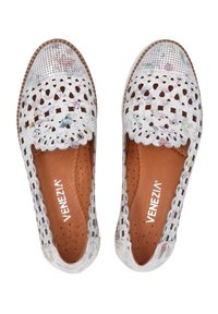White perforated leather shoes with floral patterns, scalloped edges, and a brown inner lining, featuring a flat sole and accent stitching.