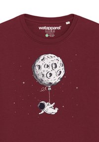 T-shirt en coton bordeaux avec un graphisme blanc représentant un astronaute tenant un ballon en forme de lune sur fond étoilé.