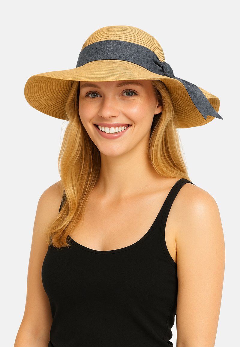 Szerok brzegi kapelusz słomkowy w jasnym beżu z ciemnoniebieską wstążką. Charakteryzuje się teksturowaną powierzchnią i miękkim, elastycznym materiałem.