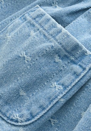 Hele sinine teksakangas nähtavate õmblustega. Omab pehmet tekstuuri ja veidi tuhmunud välimust. Kogu kangal on kulumisega seotud üksikasjad.