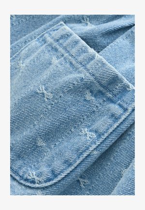 Lysblåt denimstof med synlige syninger. Har en blød tekstur og et let falmet udseende. Slidte detaljer er til stede over det hele.