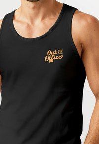 Black cotton tank top with a round neckline. Features an orange “Out of Office” graphic on the chest. Smooth texture, sleeveless design.