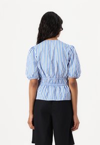 Blau-weiß gestreifte Bluse mit Puffärmeln und geraffter Taille. Baumwollstoff, Rundhalsausschnitt und figurbetonte Silhouette.