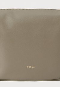 Saco de couro verde com uma textura suave, fecho em zíper e detalhe do logótipo em dourado. Forma retangular, design minimalista.