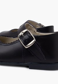 Marineblaue Lederschuhe mit einer abgerundeten Zehenpartie, gewellten Kanten und einem silbernen Schnallenriemen. Glatte Textur mit einem niedrigen Absatz und einem weichen, beigen Futter.