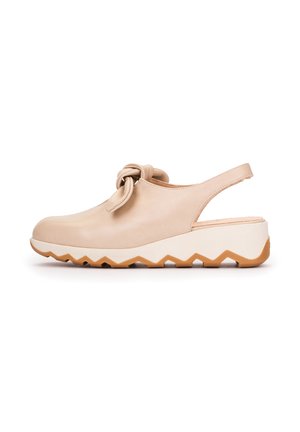 Chaussure compensée à bride arrière beige avec détail noué à l'avant et semelle en caoutchouc à motif zigzag, conçue pour un usage décontracté.