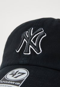 Schwarze Baseballmütze mit gesticktem weißen NY-Logo. Mit gebogenem Schirm und einem Größenetikett "47 Clean Up". Glatte Baumwollstruktur.