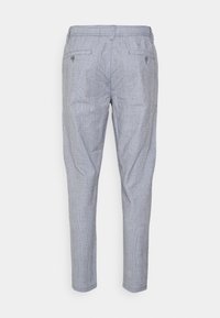 Ljusgrå smala byxor med subtilt rutmönster, två bakfickor med knapp, och bälteshällor, visade bakifrån.