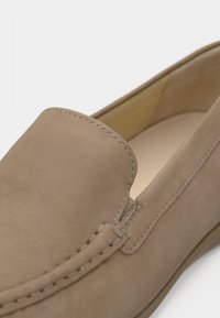 Μπεζ σουέντ παπούτσι χωρίς κορδόνια με στρογγυλεμένη μύτη, ορατή ραφή και λιτό σχεδιασμό. Το εσωτερικό διαθέτει ανοιχτόχρωμη επένδυση.