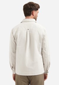 Lichtbeige overhemd met knopen, voorzien van een klassieke kraag, een rugplooi detail, lange mouwen en knoopsleeves. Geweven stofafwerking.