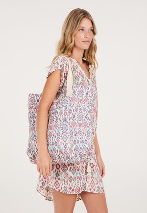 Multikleurige tote bag met complexe diamanten en bloemenpatronen, voorzien van stevige crèmekleurige banden, gemaakt van lichtgewicht stof.