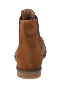 Stivaletto in suede marrone con pannelli elastici laterali, toppa per il tiro, punta tondeggiante e suola in gomma piatta. Dettagli in cucitura lungo le cuciture.