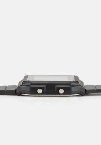 Montre numérique avec un bracelet en caoutchouc noir, un boîtier rectangulaire, deux boutons argentés et un verre lisse. Fini mat avec des accents texturés.