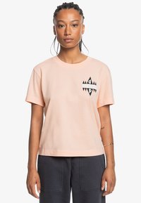 Peach cotton t-shirt with short sleeves, round neckline, and black geometric logo on chest. Straight cut and soft texture.