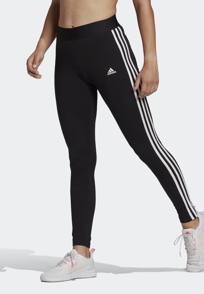 Svarta leggings med bred midjeresår, prydda med tre vita sidostrikar och en Adidas-logotyp. Tillverkade av ett elastiskt material för komfort.