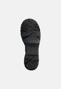 Suela de zapato de goma negra con un patrón texturizado, que presenta múltiples ranuras y detalles entrecruzados para tracción y estabilidad.