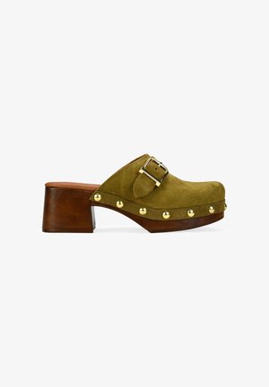 Zueco de ante verde oliva con tacón bloque de madera, tachuelas doradas decorativas a lo largo de la suela y correa con hebilla dorada ajustable.