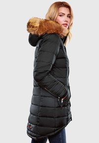 Black puffer jacket with a fur-lined hood, featuring a quilted design, zippered pockets, and a slightly elongated back hem.