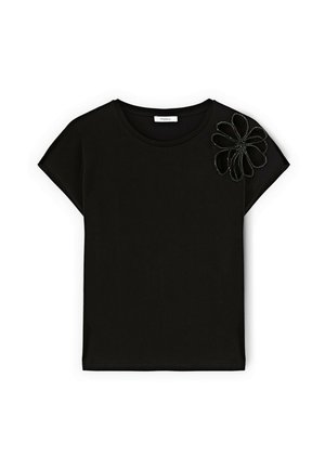 Camiseta negra de manga corta hecha de algodón con escote redondo. Presenta un aplique floral en una textura contrastante en un hombro.