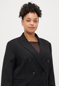 Μαύρο διπλό μπλέιζερ με κουμπιά, με καλέ лапελ, δύο μπροστινές τσέπες και μαύρα κουμπιά. Ελαφρύ ύφασμα με λεία υφή.