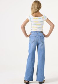 Blauwe high-waisted flared jeans van denim, met twee achterzakken en een lichte wassing, gecombineerd met een aansluitend top met een meerkleurige gestreepte print.