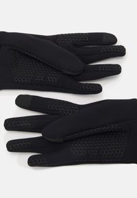 Des gants noirs en matériau doux avec des accents de texture en nid d'abeille sur les doigts et les paumes pour une meilleure adhérence.