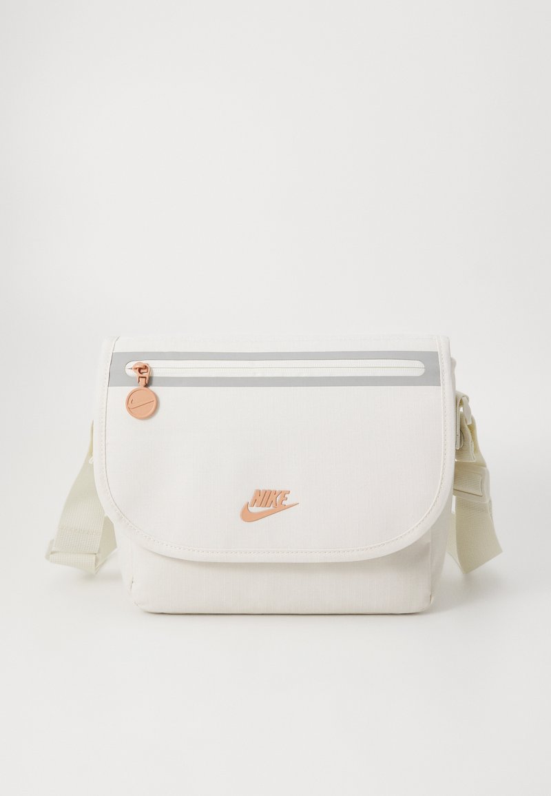 White fabric shoulder bag with a flap, silver zipper, orange logo, and adjustable strap. Features textured material and minimalistic design.