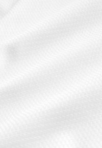 Gros plan sur un tissu blanc doux avec un motif chevron tissé subtil et des plis légers créant texture et profondeur.