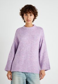 Ljubičasti pleteni pulover s rebrastim rubom i širokim rukavima, koji se odlikuje mekom, pahuljastom teksturom i suptilnim ružičastim točkicama raspoređenim po cijeloj površini.