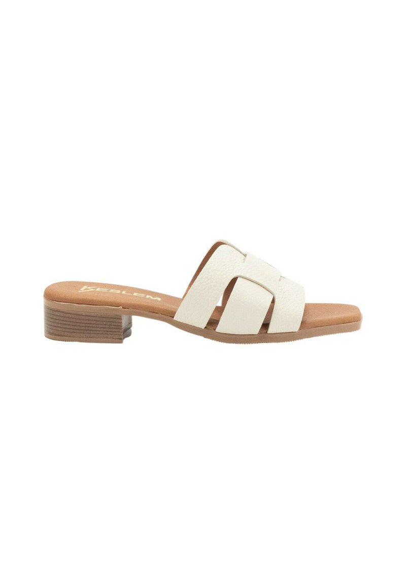 Sandalias deslizantes de cuero blanco que presentan un diseño de tiras cruzadas y un bajo tacón de bloque de madera. La suela es de color tostado con un acabado texturizado.