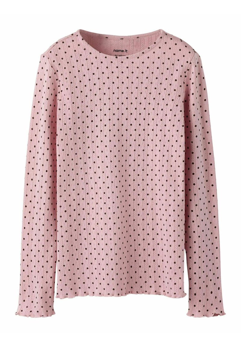 Różowy sweter z długim rękawem o prążkowanej fakturze, ozdobiony wzorem małych czarnych kropek i zaokrąglonym dekoltem. Krawędzie lekko postrzępione.