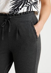 Mörkgrå joggingsbyxor i mjukt tyg, med dragsko i midjan, fluffiga fickor och en skräddarsydd passform.