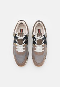 Des chaussures de sport brunes et grises avec des lacets blancs, en matériaux en daim et en mesh, avec des accents contrastants bleu marine et jaunes, et une semelle en caoutchouc.
